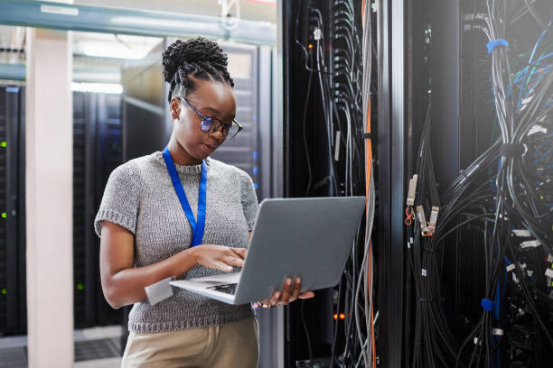 shot of a young woman using a laptop in a server room